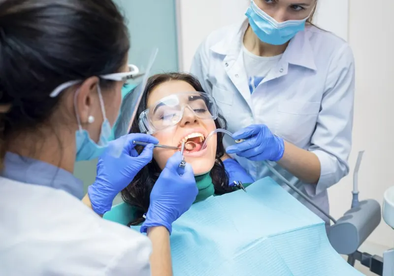 Dois dentistas da OdontoSin atendendo uma paciente